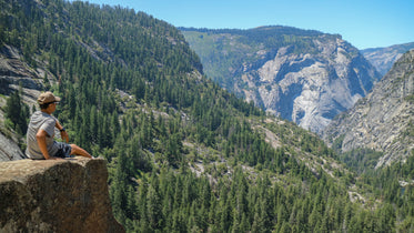 sitting on ledge looking at mountains and trees