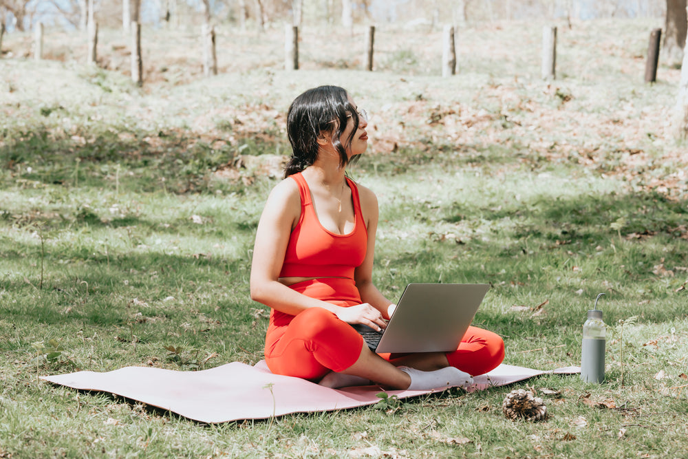 sitting on yoga mat while working on a laptop outdoors