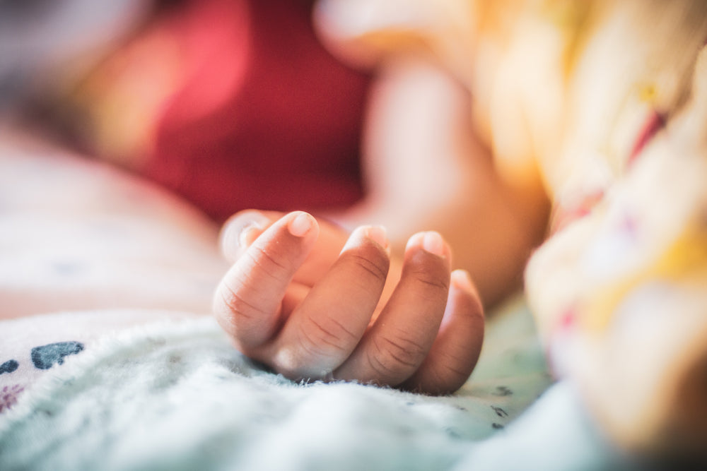 small childs hand on blue blanket