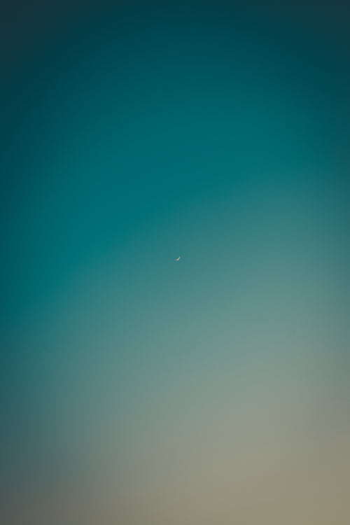 small crescent moon in blue sky