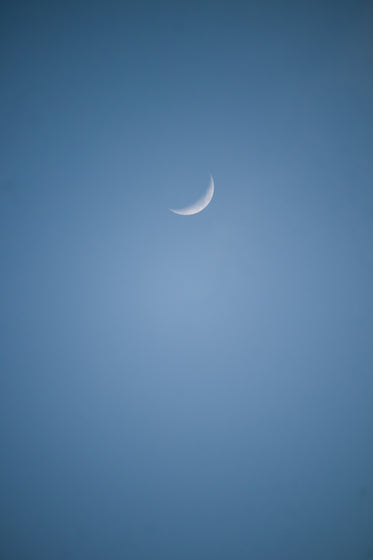 small sliver of the moon in a blue sky