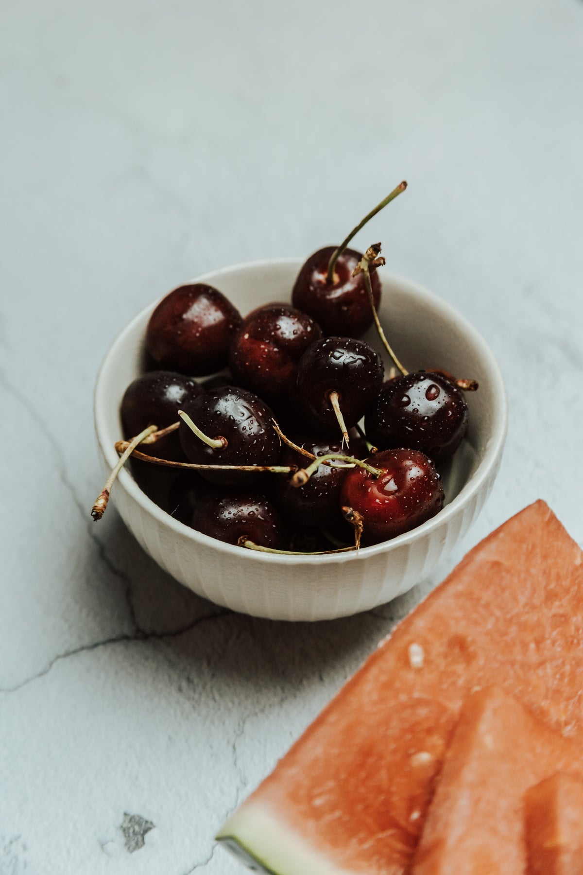small white bowl filled with ripe cherries