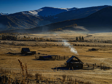 Small Wooden Structures In A Brown Grassy Field