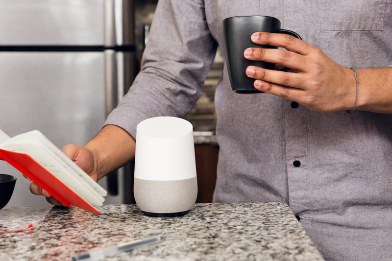 a man in a gray shirt is holding a cup of coffee - smart home device on counter