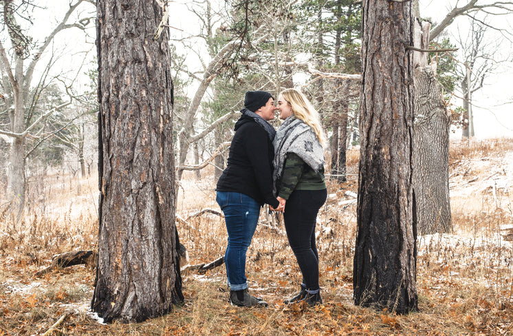 Smiling Couple Stand Nose To Nose Between Two Trees