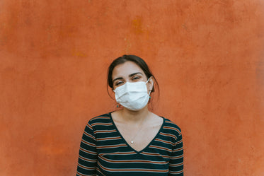 smiling person in a facemask by an orange wall