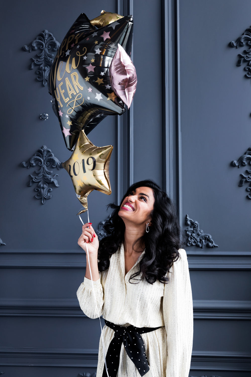 smiling woman holding new year's eve balloons