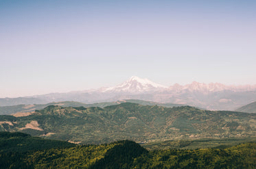 snowy mountains over grassy hills