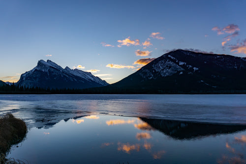 snowy mountains reflect in water at sunrise