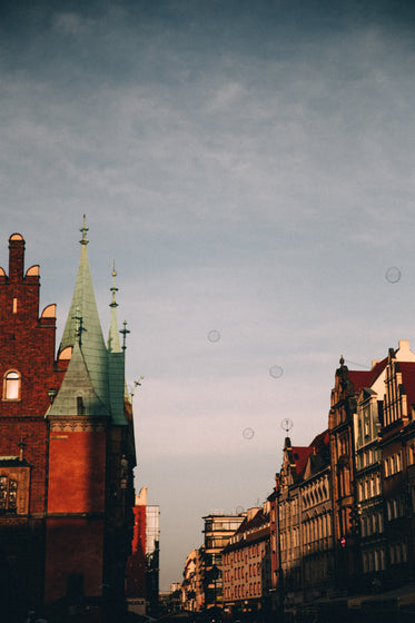soap bubbles float over red brick spires of a town