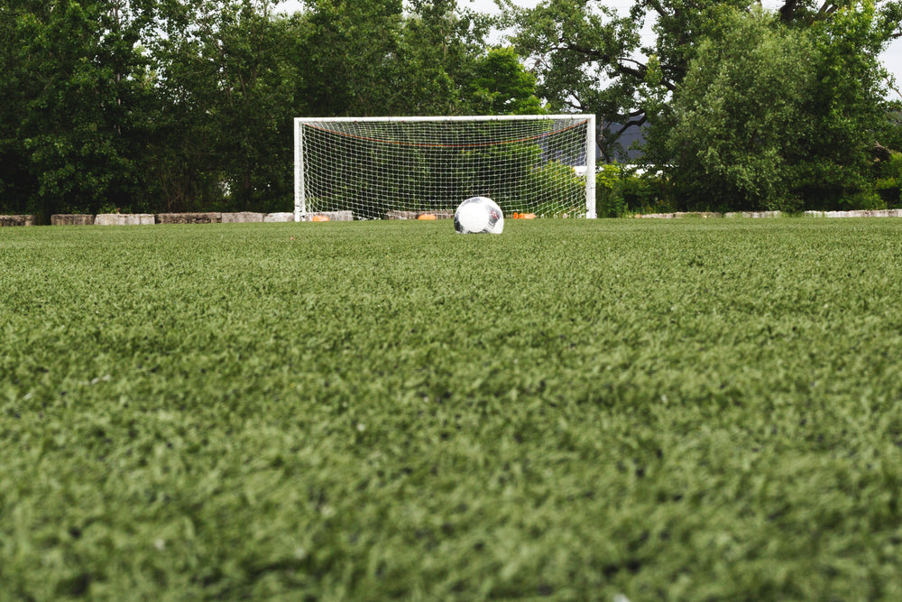 bola de futebol no campo com o gol atrás