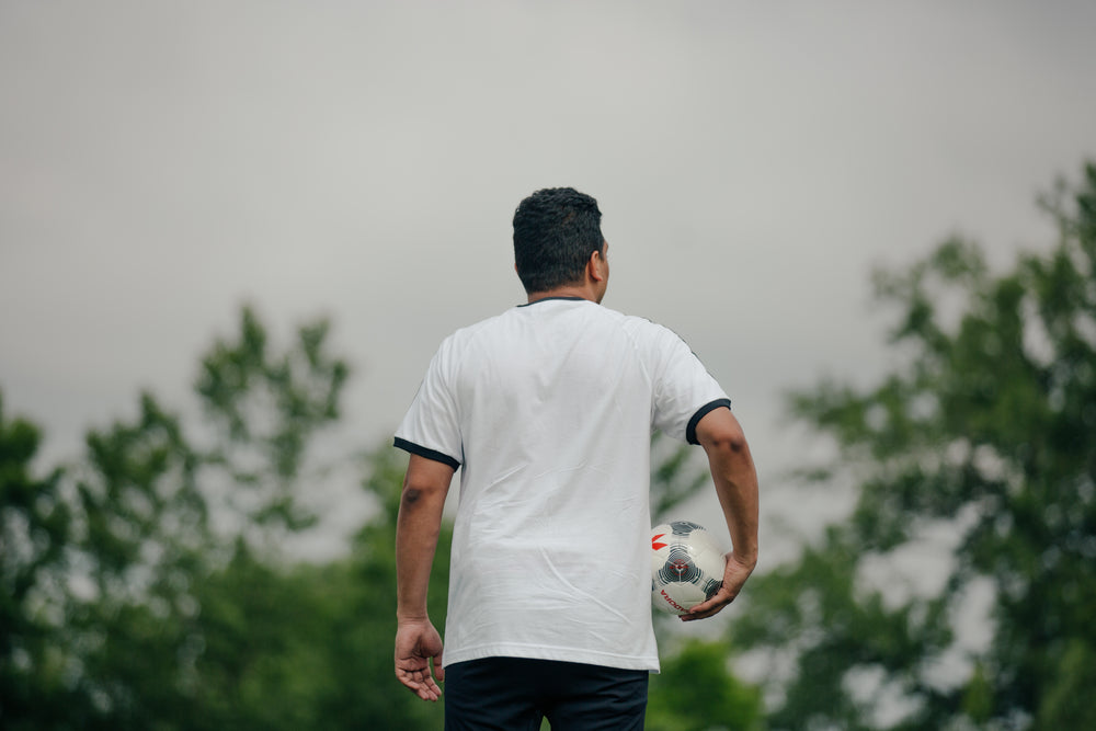 jogador de futebol segurando a bola e olhando ao redor