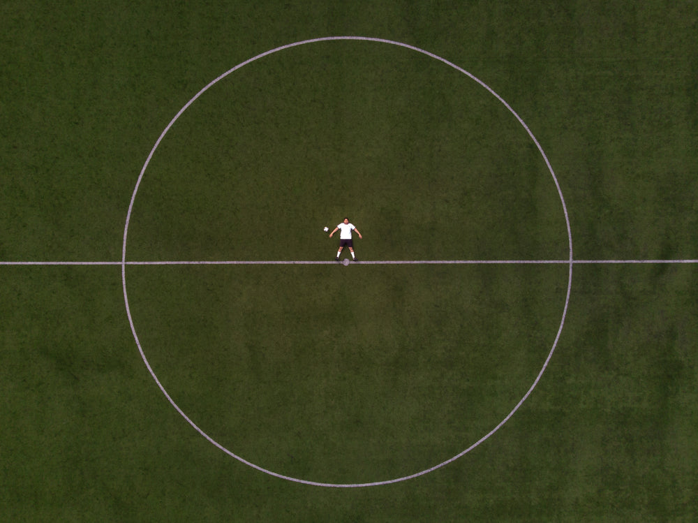 jogador do futebol deitado no círculo do meio do campo