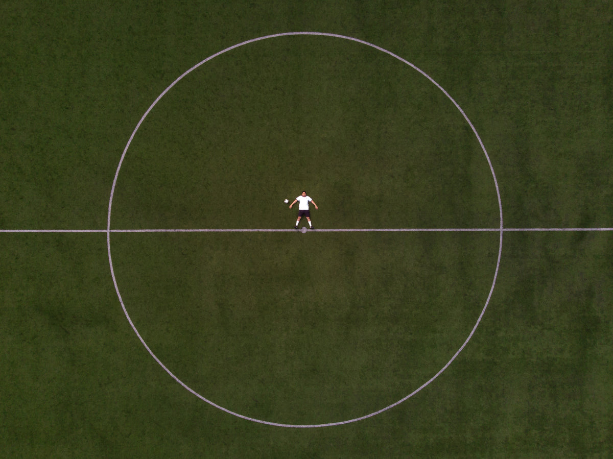 jogador do futebol deitado no círculo do meio do campo