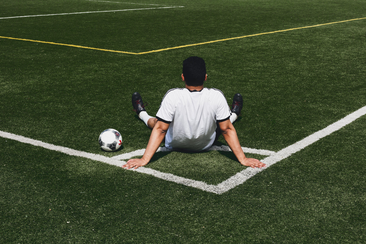 soccer player sits at field corner