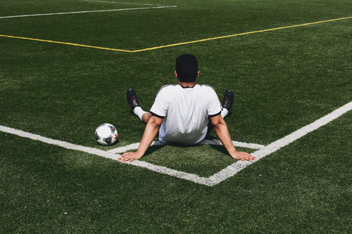soccer player sits at field corner