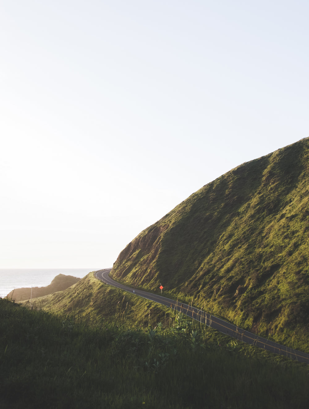 solitary highway curves around lush green hillside