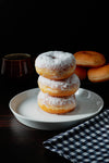 stack of doughnuts with white powered tops on a plate