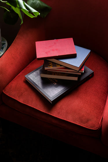 stack of hardcover books on a red armchair