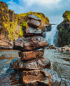 stack of wet rocks with a waterfall behind