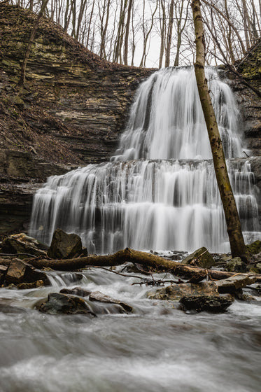 standing in the river at the base of cascading waterfalls