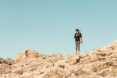 standing on rocky hill looking down at a phone