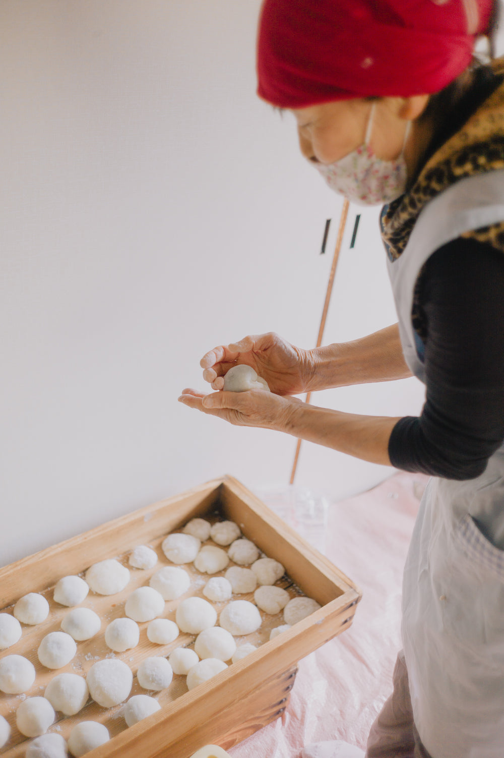 standing over wooden box of small balls of dough