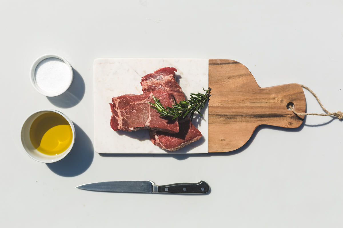 steaks oil salt knife and a cutting board