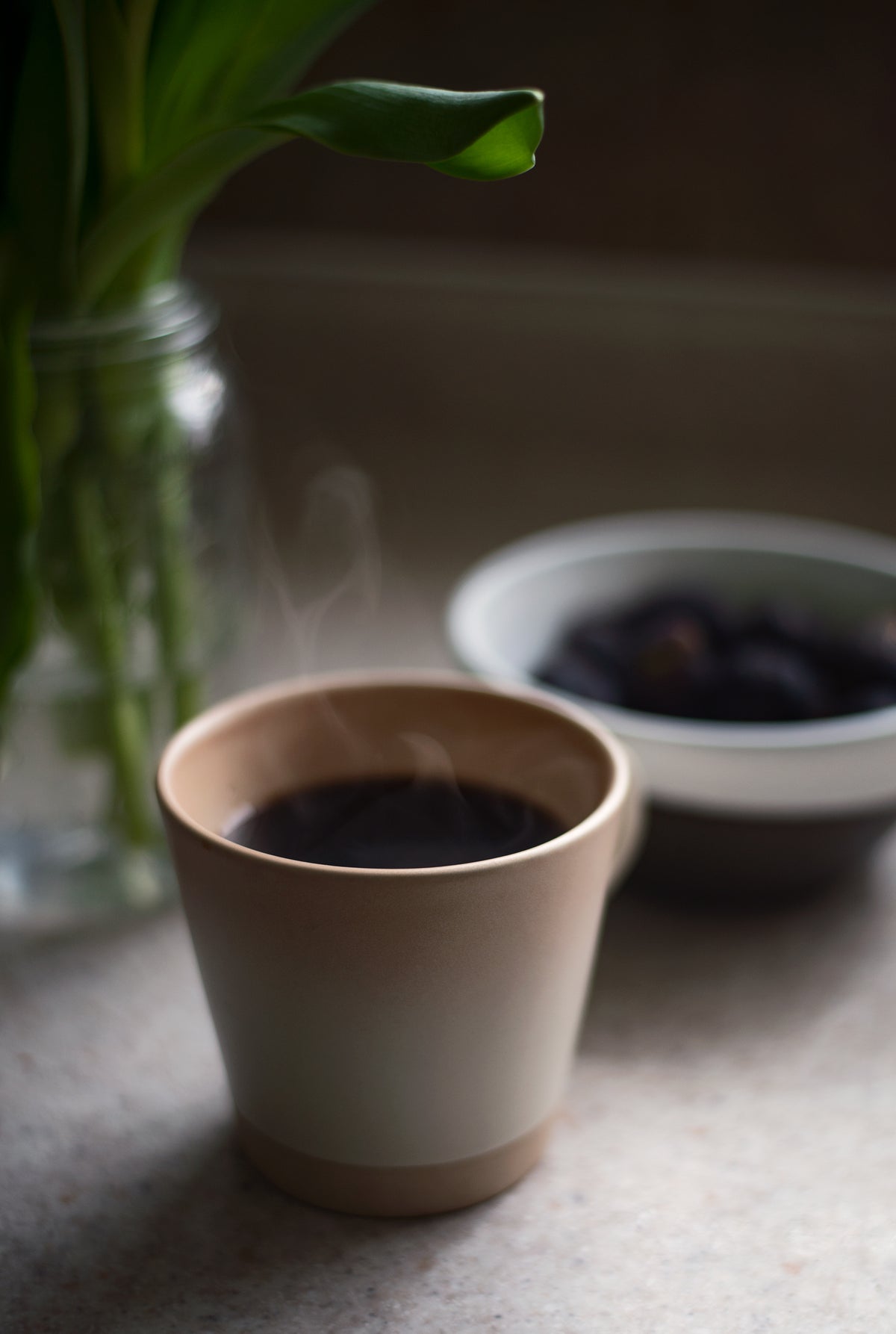 steaming cup of black coffee sits on a kitchen counter