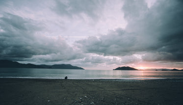 still beach at sunset with person crouching