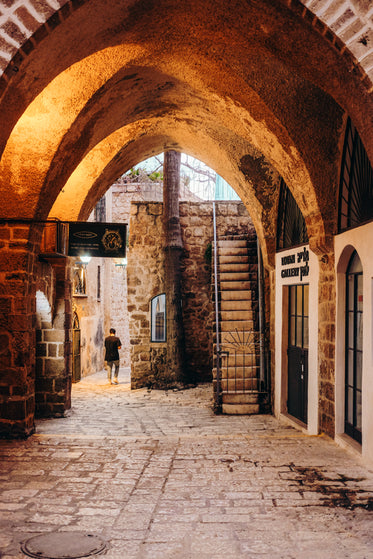 stone archway covers a walkway with person in distance