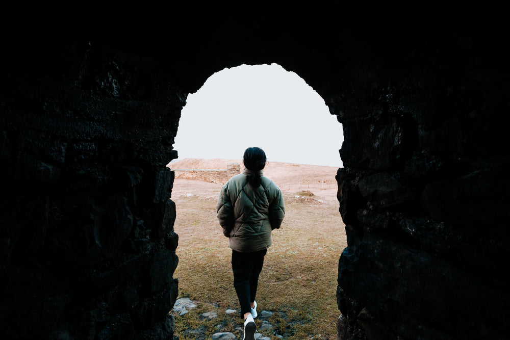 stone archway frames a person walking to beach