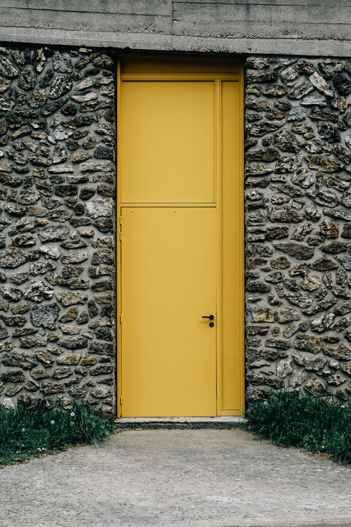 stone building with a thin bright yellow door