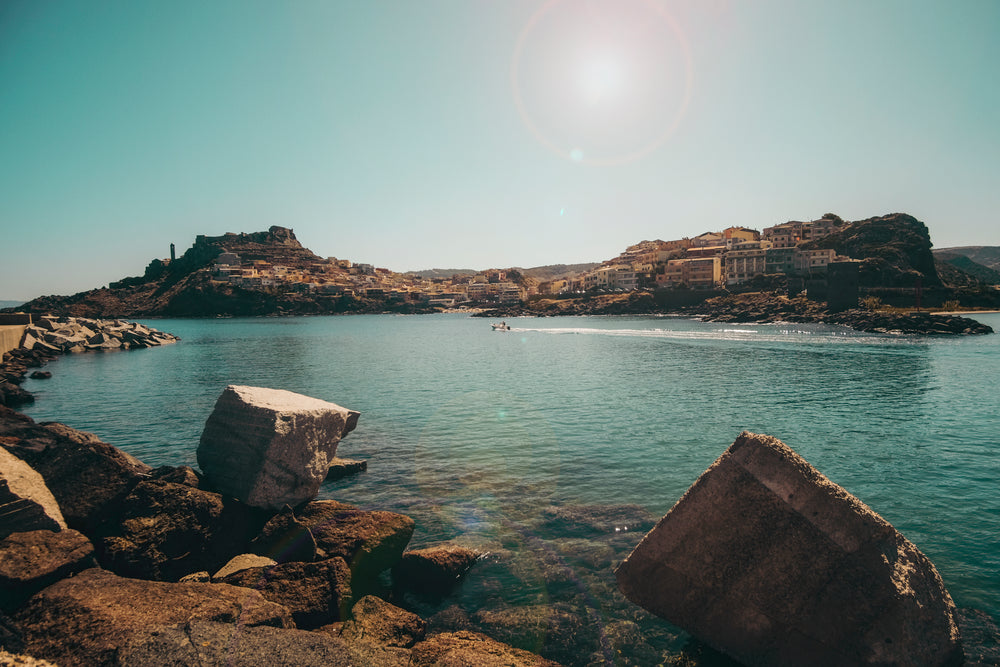 stone shoreline and aqua blue water with a single boat