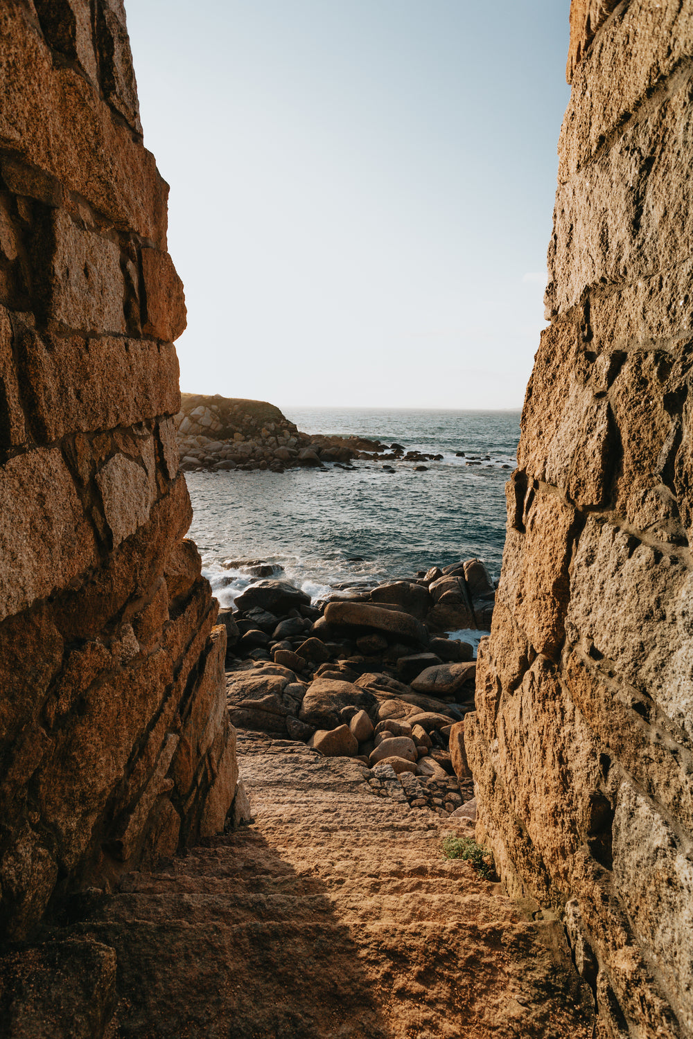 stone stairs lead to a stone covered shore with waves