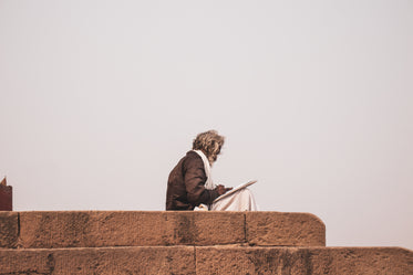 stone steps with a person sitting with white paper on their lap