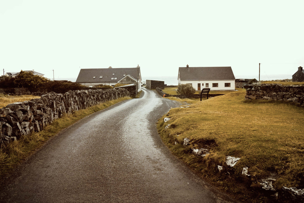 stone walls beside gravel road and rural buildings