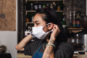 store owner places face mask over her face