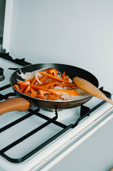 stove top and pan filled with onions and peppers