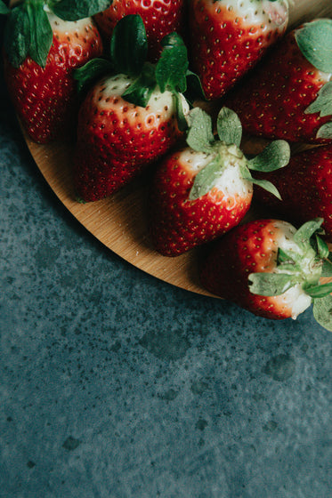 strawberries on a wooden plate over black surface