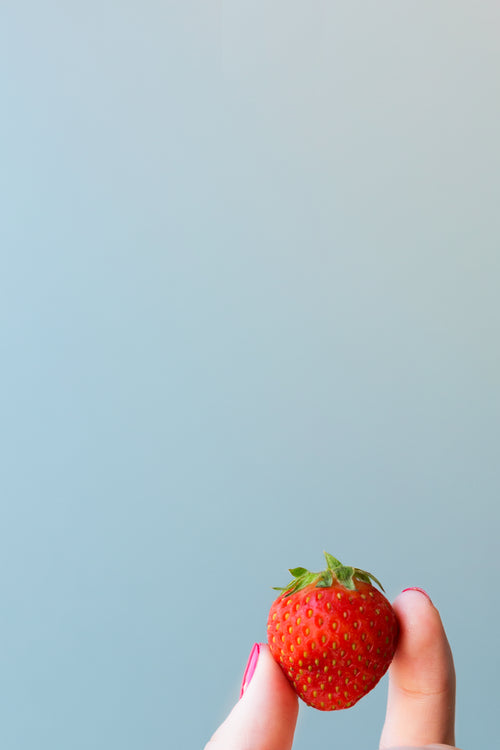 strawberry in hand blue background