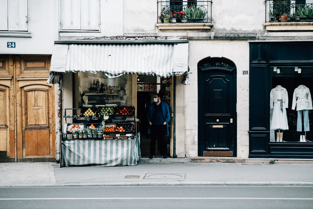 street with a fruit stand and a person in a facemask