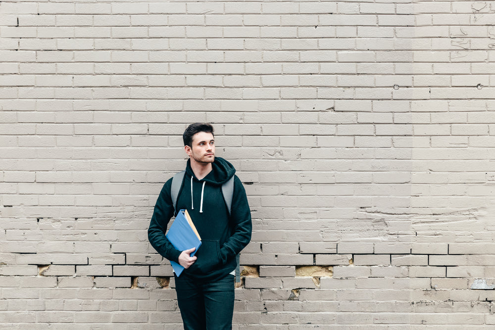 student leaning against brick wall