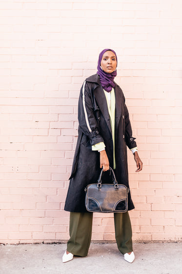 stylish model poses holding leather handbag
