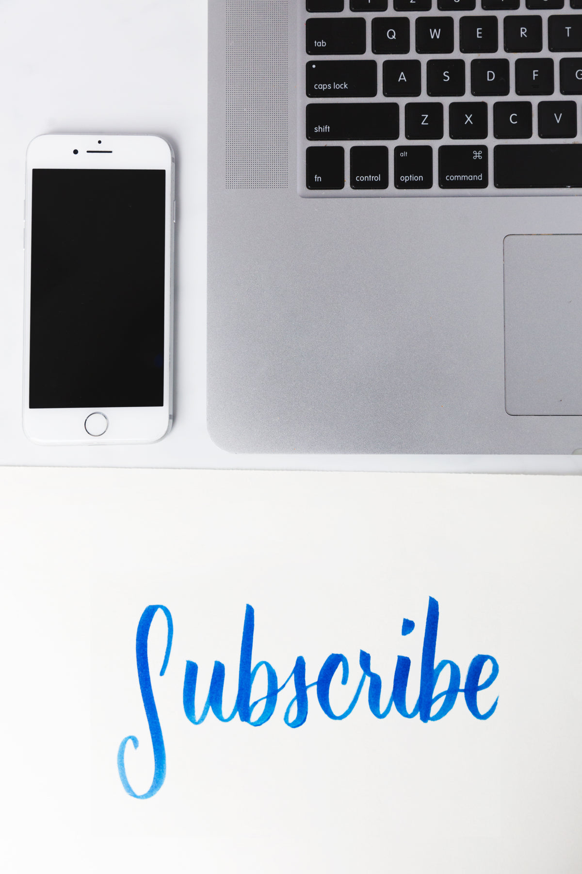 subscribe written under a phone and laptop