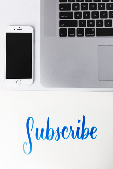 subscribe written under a phone and laptop