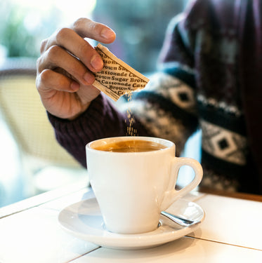 sugar being added to cup of coffee