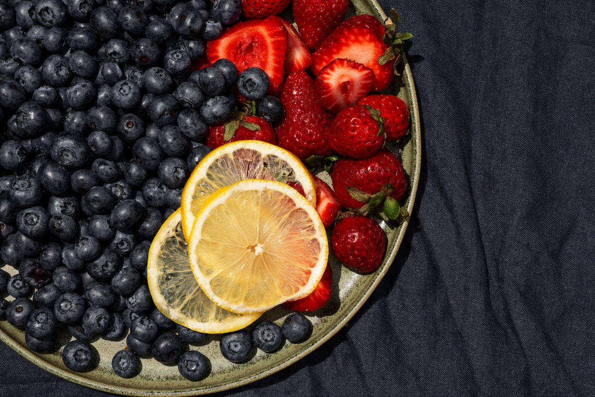 summer fruits on a green plate with a blue tablecloth