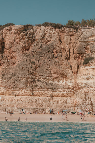 sun cracked cliffs overlook bathers on a sandy beach