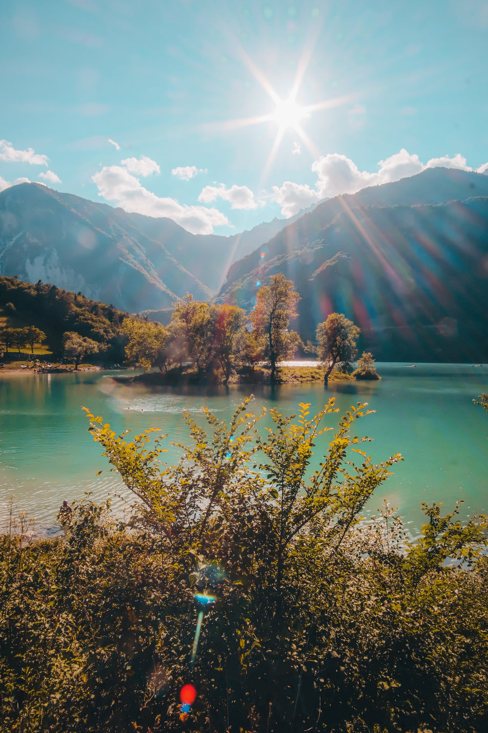 sun flare over hill tops and a still lake